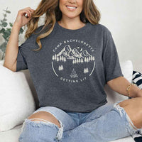 May include Dark Heather camp themed Bachelorette t shirts with fun outdoor slogans cozy vibes bridal squad outfits perfect for camping trip celebrations and girls getaway!