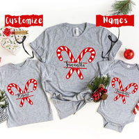 May include a festive Christmas t-shirt featuring a candy cane design and personalized family name, laid flat with candy canes and holiday decorations.