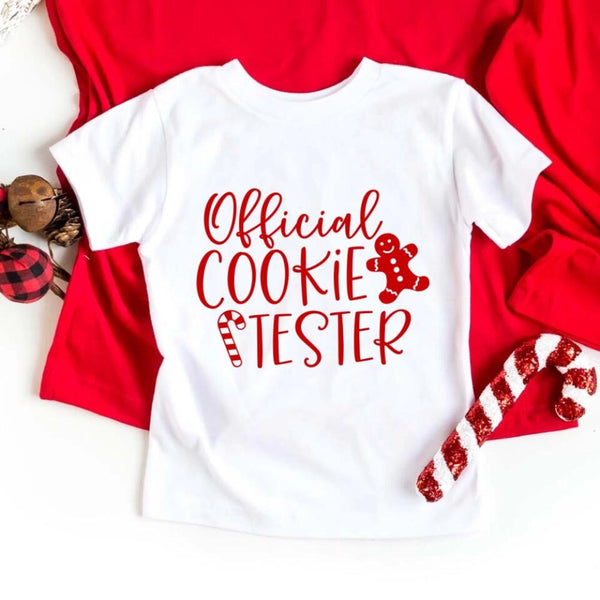 May include a Christmas-themed t-shirt reading “Official Cookie Baker and Tester,” featuring festive colors and cookie graphics, ideal for holiday bakers.