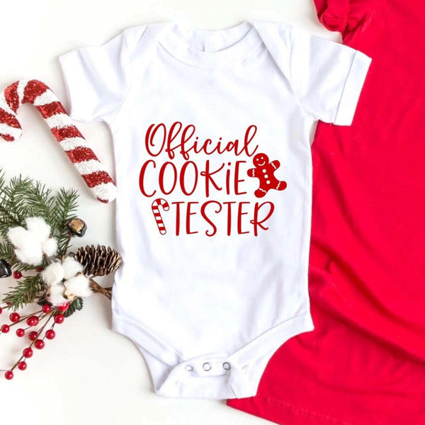 May include a Christmas-themed t-shirt reading “Official Cookie Baker and Tester,” featuring festive colors and cookie graphics, ideal for holiday bakers.