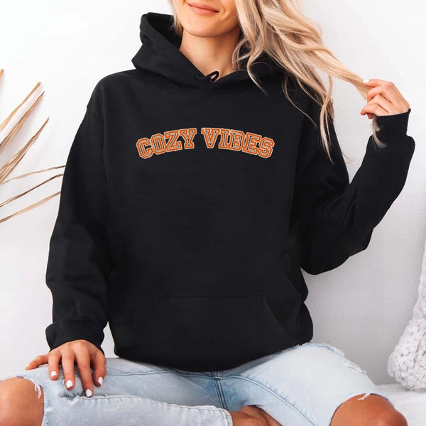 May include a unisex fall hoodie with “Cozy Vibes” text, featuring a soft fleece texture and autumn-inspired colors.