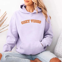 May include a unisex fall hoodie with “Cozy Vibes” text, featuring a soft fleece texture and autumn-inspired colors.