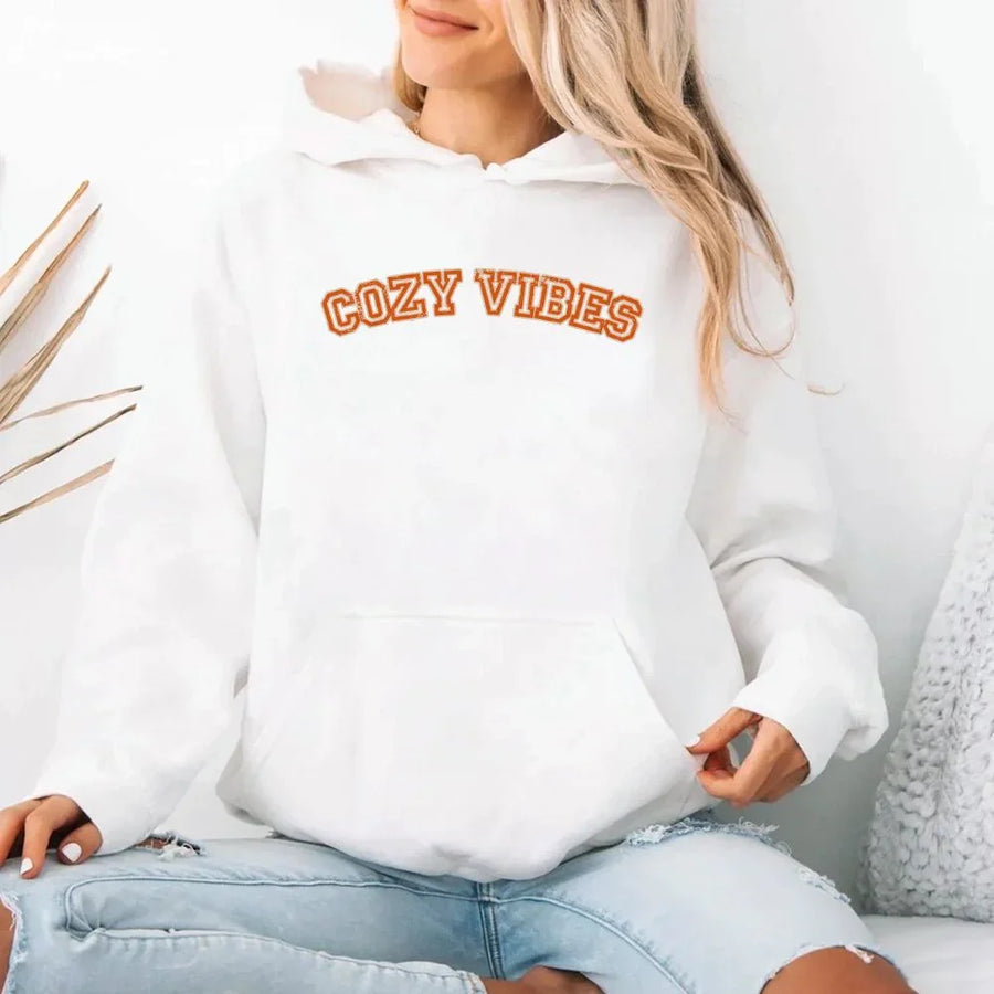 May include a unisex fall hoodie with “Cozy Vibes” text, featuring a soft fleece texture and autumn-inspired colors.