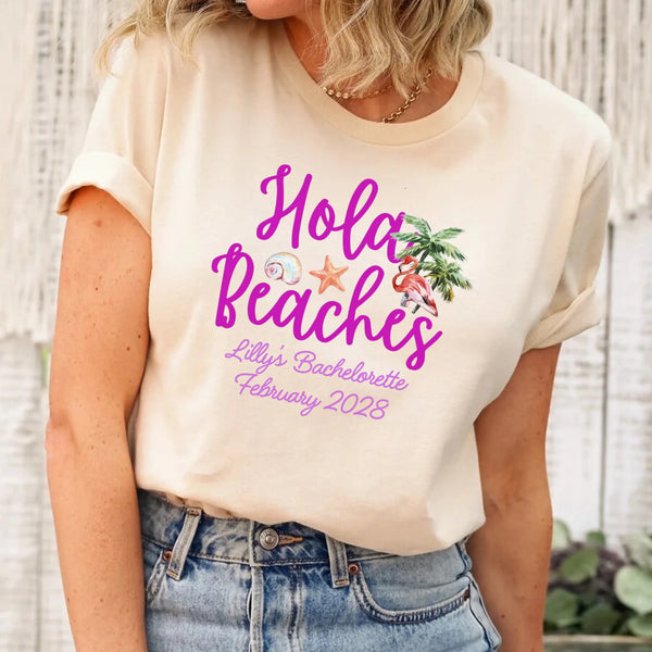 May include Cream bridesmaids wearing custom matching beach bachelorette T-shirts, relaxed seaside setting with sand and ocean backdrop, coordinated outfits, smiling and celebrating together outdoors!
