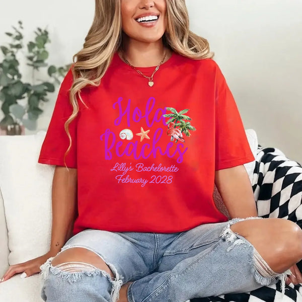 May include Red bridesmaids wearing custom matching beach bachelorette T-shirts, relaxed seaside setting with sand and ocean backdrop, coordinated outfits, smiling and celebrating together outdoors!
