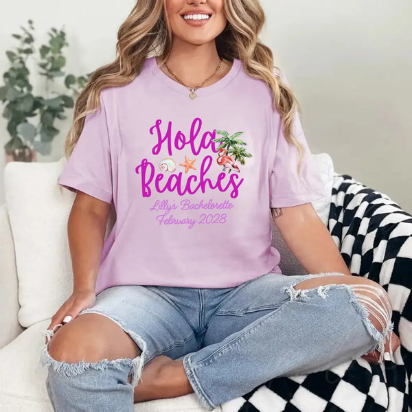 May include Lilac bridesmaids wearing custom matching beach bachelorette T-shirts, relaxed seaside setting with sand and ocean backdrop, coordinated outfits, smiling and celebrating together outdoors!