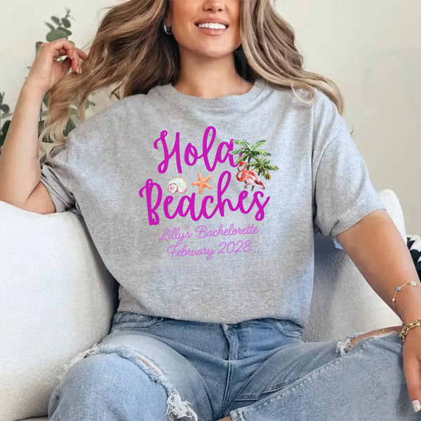 May include Grey bridesmaids wearing custom matching beach bachelorette T-shirts, relaxed seaside setting with sand and ocean backdrop, coordinated outfits, smiling and celebrating together outdoors!