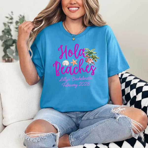 May include Sapphire bridesmaids wearing custom matching beach bachelorette T-shirts, relaxed seaside setting with sand and ocean backdrop, coordinated outfits, smiling and celebrating together outdoors!
