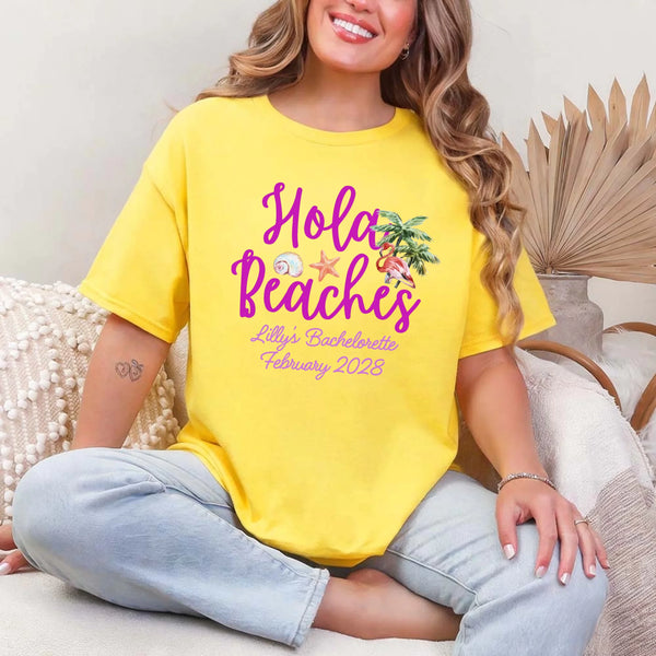May include Daisy bridesmaids wearing custom matching beach bachelorette T-shirts, relaxed seaside setting with sand and ocean backdrop, coordinated outfits, smiling and celebrating together outdoors!