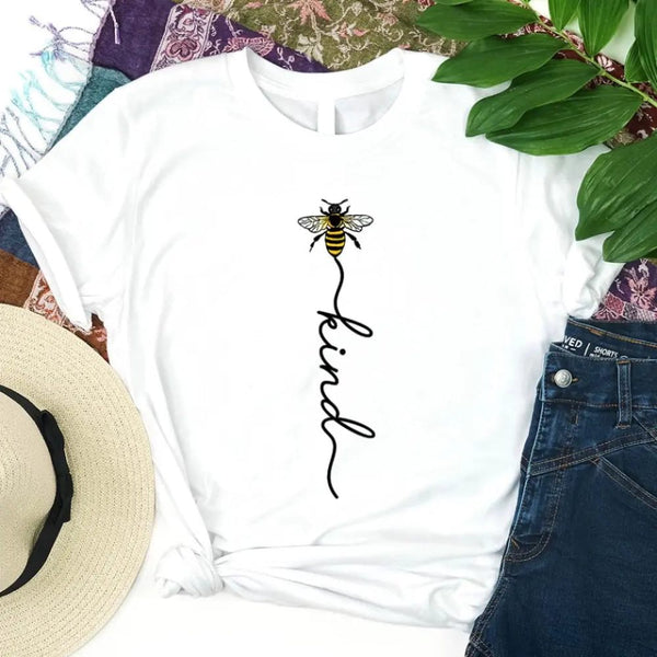 May include an inspirational t-shirt design featuring the phrase “Bee Kind” in flowing script lettering, often paired with a small bee graphic that adds a gentle, uplifting touch to the message.