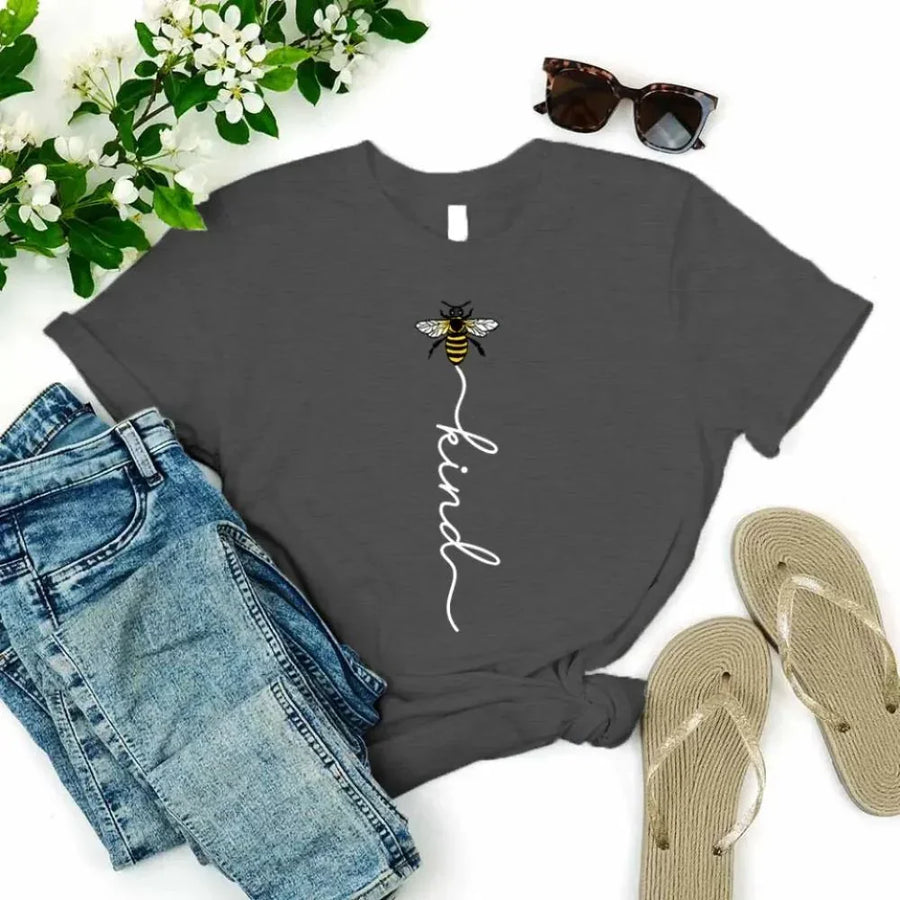 May include an inspirational t-shirt design featuring the phrase “Bee Kind” in flowing script lettering, often paired with a small bee graphic that adds a gentle, uplifting touch to the message.