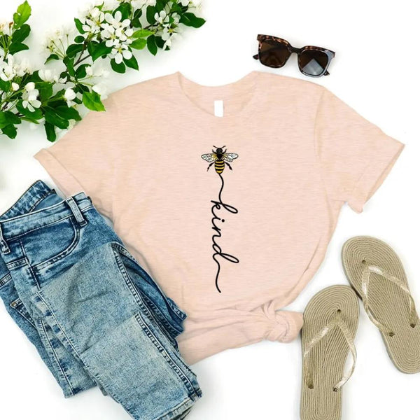 May include an inspirational t-shirt design featuring the phrase “Bee Kind” in flowing script lettering, often paired with a small bee graphic that adds a gentle, uplifting touch to the message.
