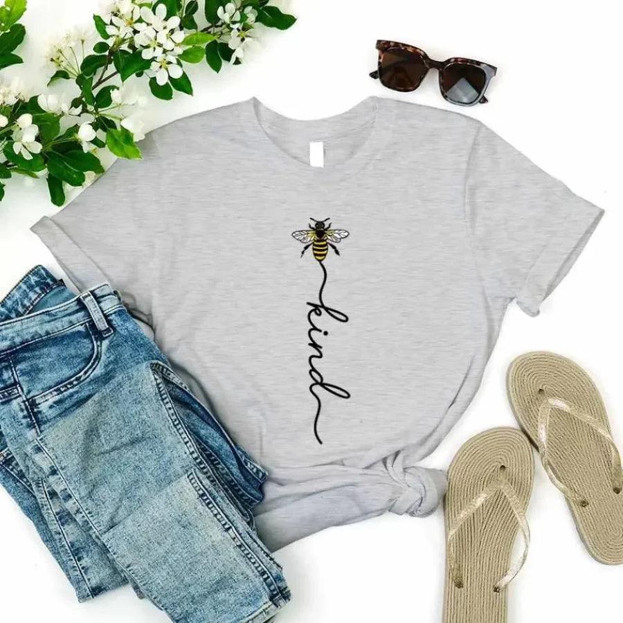 May include an inspirational t-shirt design featuring the phrase “Bee Kind” in flowing script lettering, often paired with a small bee graphic that adds a gentle, uplifting touch to the message.
