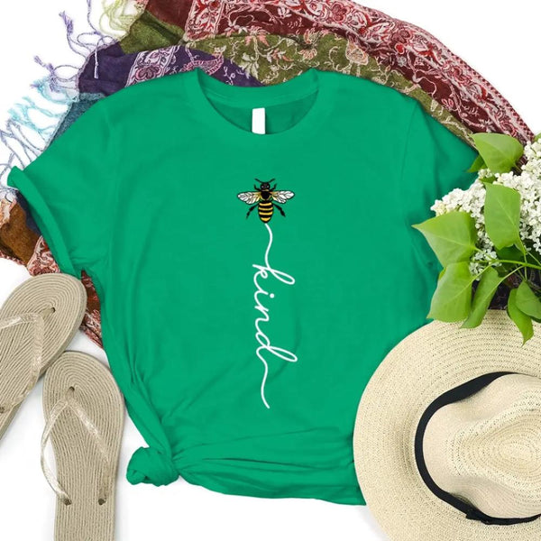 May include an inspirational t-shirt design featuring the phrase “Bee Kind” in flowing script lettering, often paired with a small bee graphic that adds a gentle, uplifting touch to the message.
