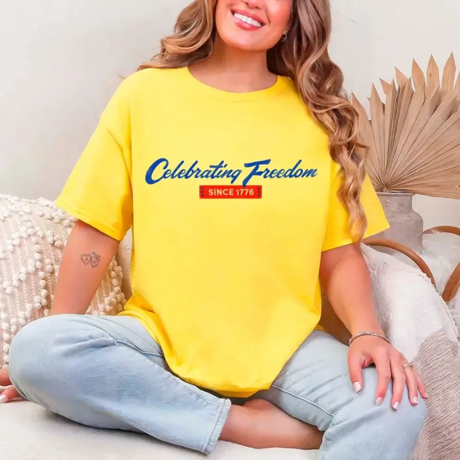 Person wearing a yellow t-shirt with 'Celebrating Freedom Since 1776' text, sitting on a couch.