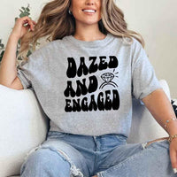 May include Grey group in colorful tie-dye shirts reading “Dazed & Engaged,” smiling at a bachelorette party, with bride in veil and fun, festive vibe!

