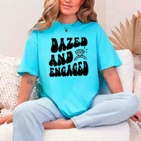 May include Turquoise group in colorful tie-dye shirts reading “Dazed & Engaged,” smiling at a bachelorette party, with bride in veil and fun, festive vibe!