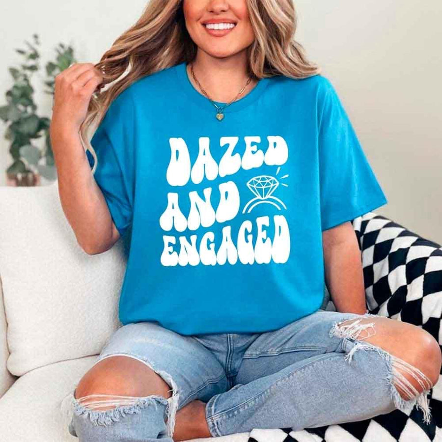 May include Sapphire group in colorful tie-dye shirts reading “Dazed & Engaged,” smiling at a bachelorette party, with bride in veil and fun, festive vibe!