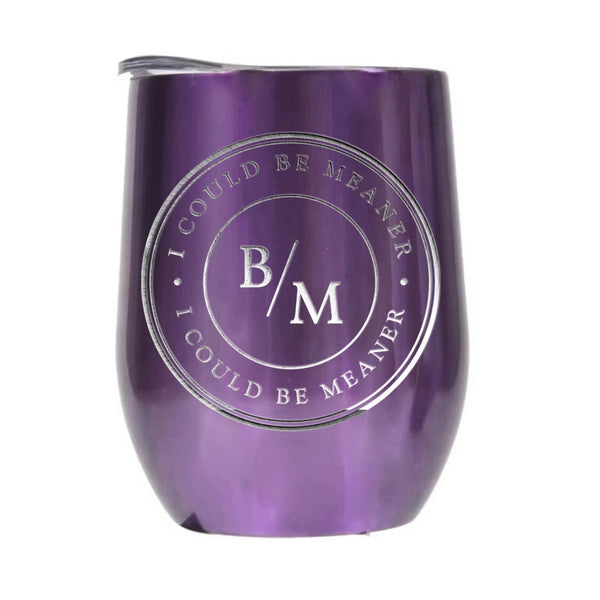 May include a wine tumbler displayed on a wooden surface, featuring a circular black design with the text “I COULD BE MEANER” repeated around the outer ring and the initials “B/M” centered inside. 