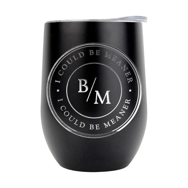 May include a wine tumbler displayed on a wooden surface, featuring a circular black design with the text “I COULD BE MEANER” repeated around the outer ring and the initials “B/M” centered inside. 