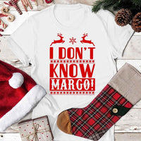 White t-shirt with 'I DON'T KNOW MARGO!' text, surrounded by Christmas items on a wooden surface.