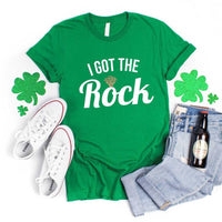 May include a couple wearing matching St. Patrick’s Day engagement t-shirts with the phrase “I Got The Rock”.