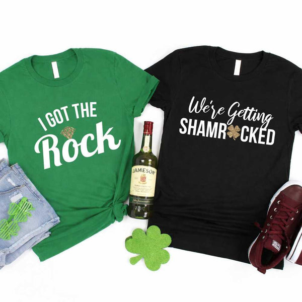 May include a couple wearing matching St. Patrick’s Day engagement t-shirts with the phrase “I Got The Rock”.