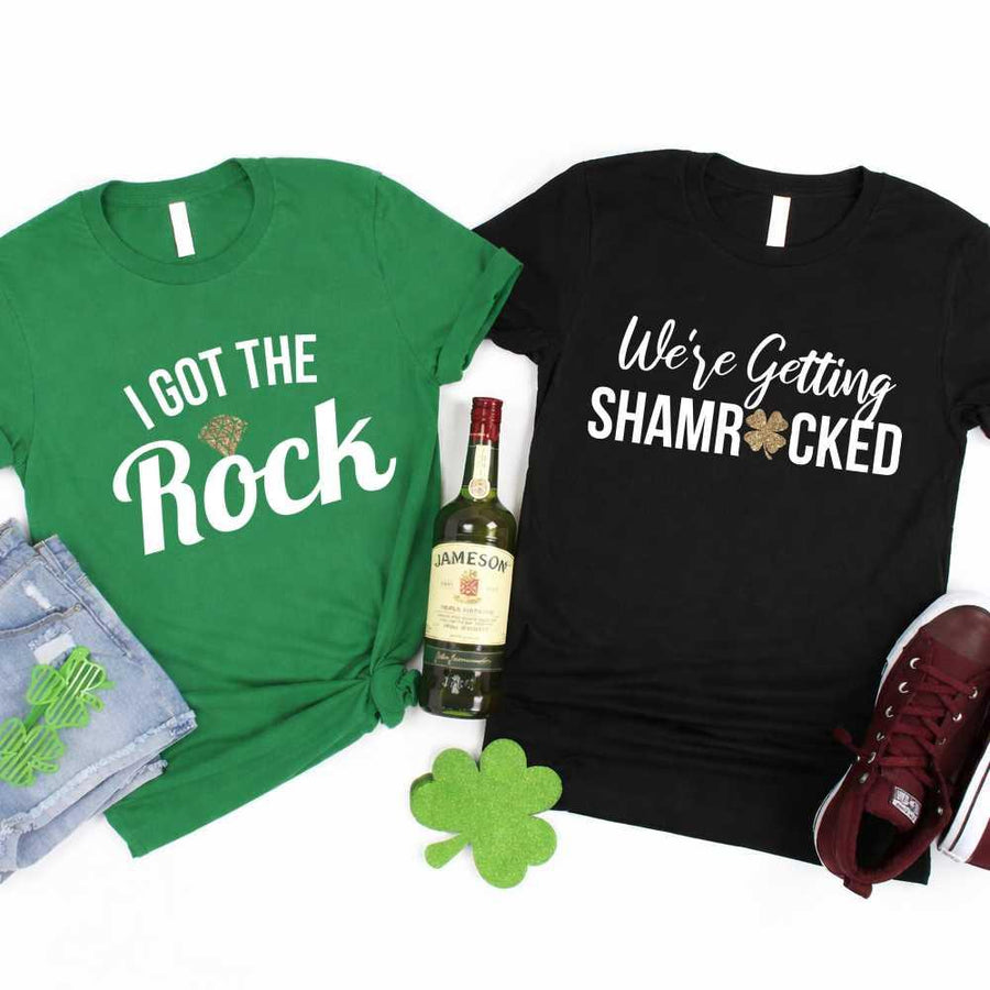 May include a couple wearing matching St. Patrick’s Day engagement t-shirts with the phrase “I Got The Rock”.