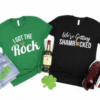 May include a couple wearing matching St. Patrick’s Day engagement t-shirts with the phrase “I Got The Rock”.
