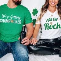 May include a couple wearing matching St. Patrick’s Day engagement t-shirts with the phrase “I Got The Rock”.