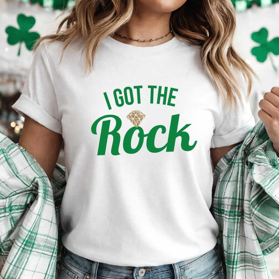 May include a couple wearing matching St. Patrick’s Day engagement t-shirts with the phrase “I Got The Rock”.