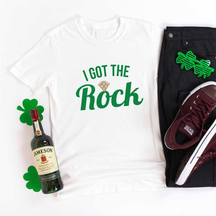 May include a couple wearing matching St. Patrick’s Day engagement t-shirts with the phrase “I Got The Rock”.