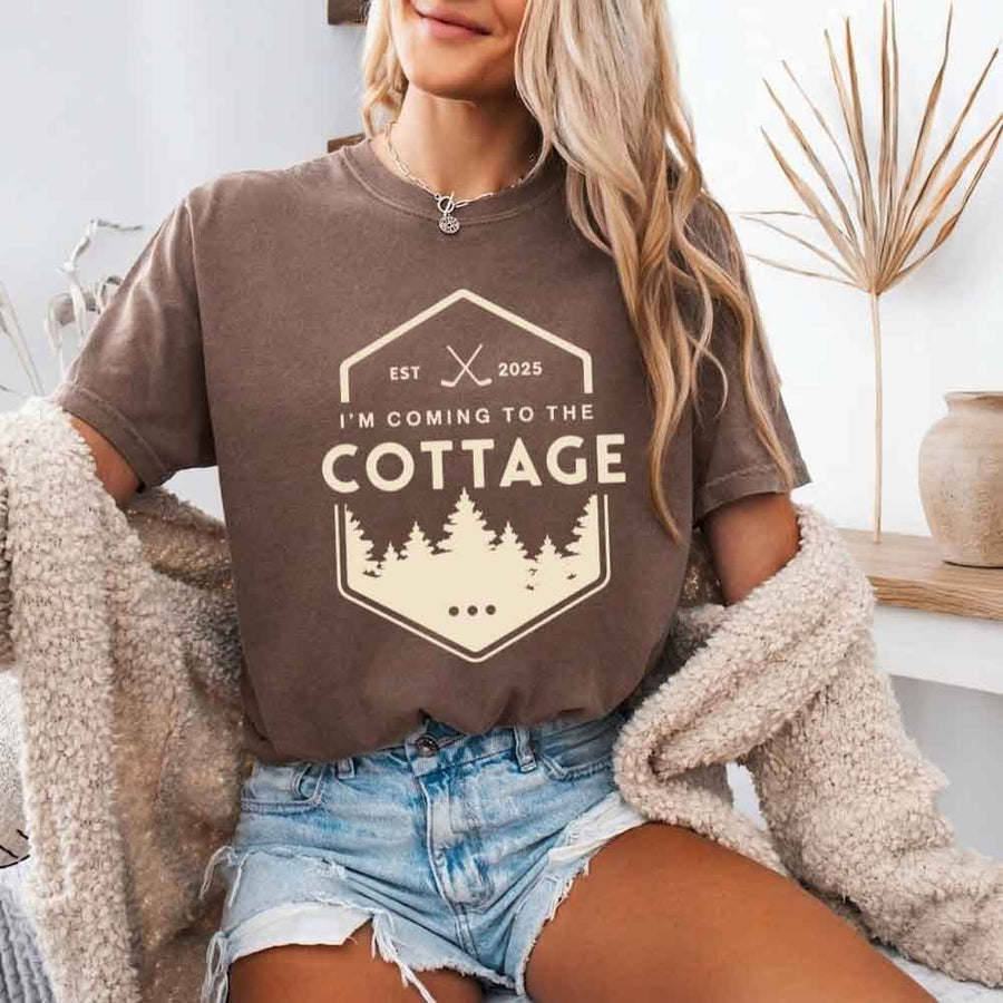 May include a person wearing an Espresso I’m Coming to the Cottage T-Shirt featuring rivalry inspired graphic design and relaxed fit.