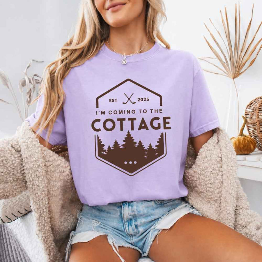 May include a person wearing a Orchid  I’m Coming to the Cottage T-Shirt featuring rivalry inspired graphic design and relaxed fit.
