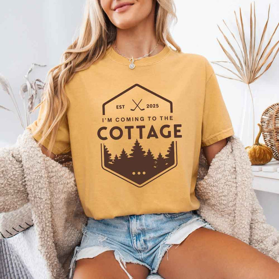 May include a person wearing a Mustard I’m Coming to the Cottage T-Shirt featuring rivalry inspired graphic design and relaxed fit.
