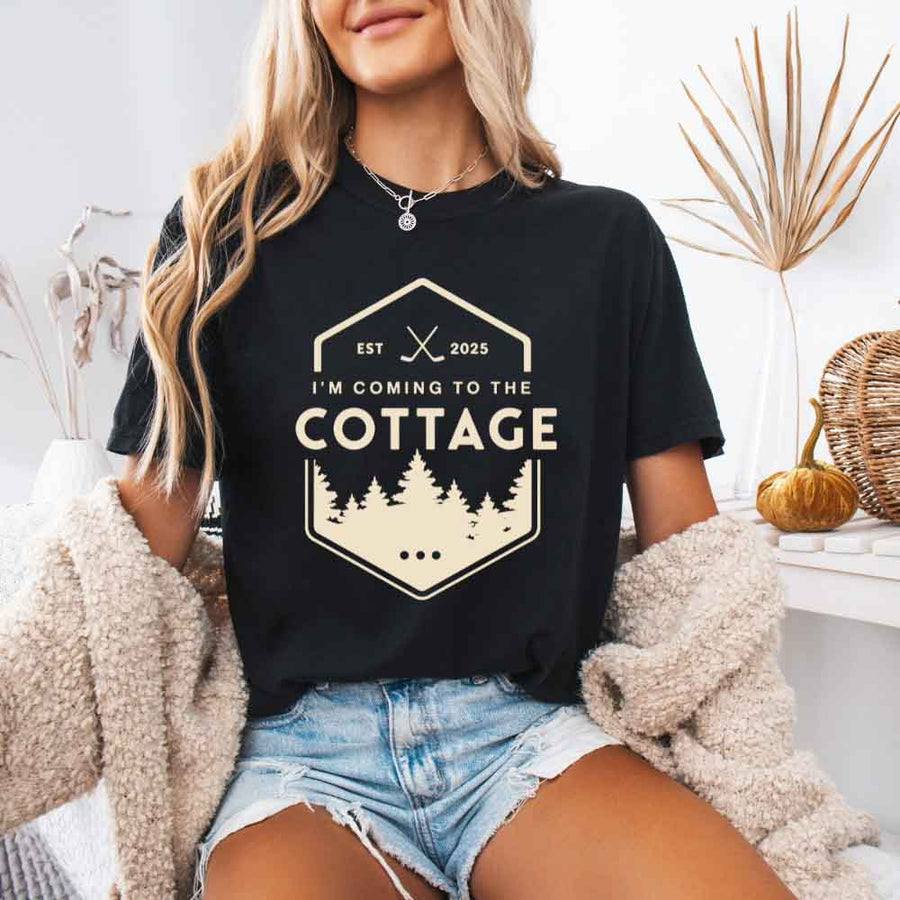 May include a person wearing a Black I’m Coming to the Cottage T-Shirt featuring rivalry inspired graphic design and relaxed fit.