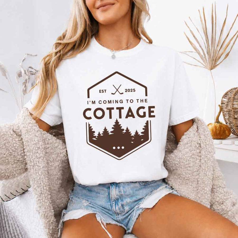 May include a person wearing a White I’m Coming to the Cottage T-Shirt featuring rivalry inspired graphic design and relaxed fit.