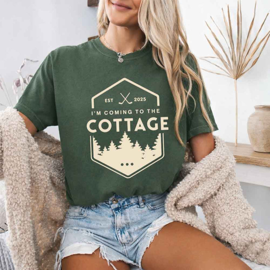 May include a person wearing a Moss I’m Coming to the Cottage T-Shirt featuring rivalry inspired graphic design and relaxed fit.