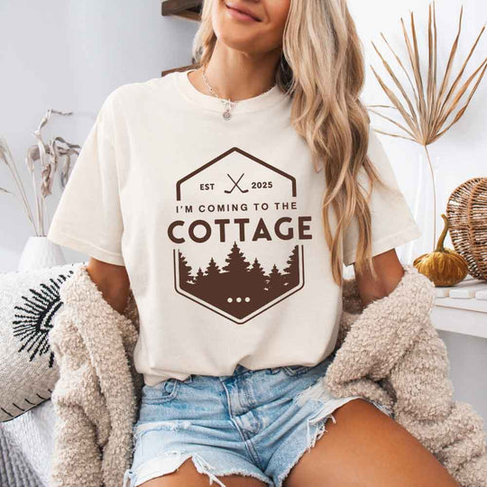 May include a person wearing an Ivory I’m Coming to the Cottage T-Shirt featuring rivalry inspired graphic design and relaxed fit.