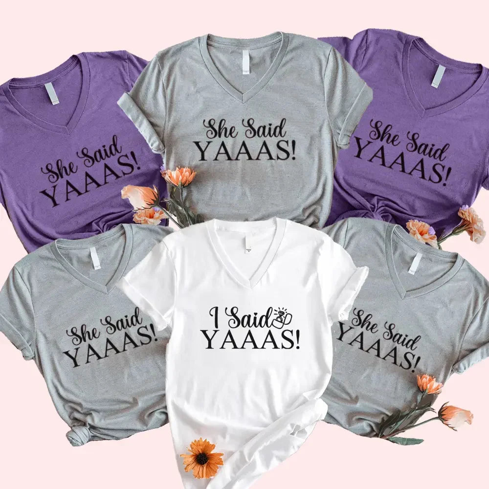 Collection of t-shirts with 'She Said YAAAS!' and 'I Said YAAAS!' text on a pink background.