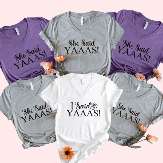 Collection of t-shirts with 'She Said YAAAS!' and 'I Said YAAAS!' text on a pink background.