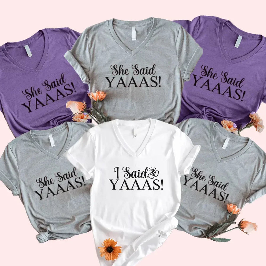 Collection of t-shirts with 'She Said YAAAS!' and 'I Said YAAAS!' text on a pink background.