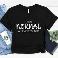 May include a women’s t-shirt with the phrase “I Was Normal a Few Kids Ago,” displayed flat or worn by a mom, highlighting a humorous motherhood theme.