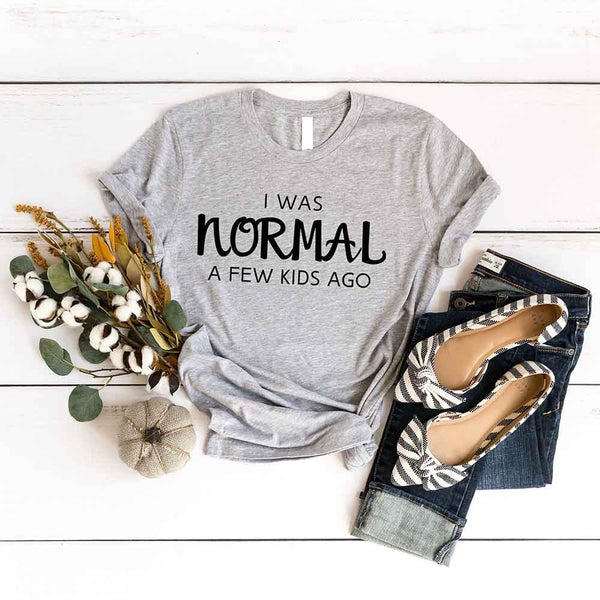 May include a women’s t-shirt with the phrase “I Was Normal a Few Kids Ago,” displayed flat or worn by a mom, highlighting a humorous motherhood theme.