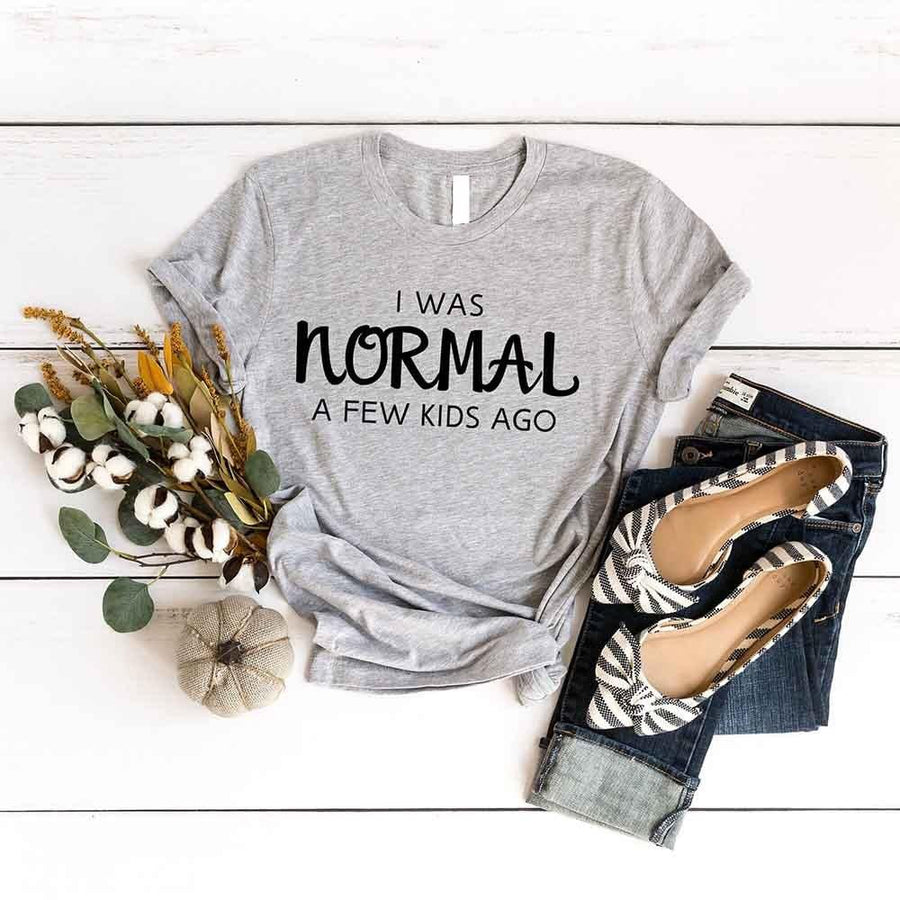 May include a women’s t-shirt with the phrase “I Was Normal a Few Kids Ago,” displayed flat or worn by a mom, highlighting a humorous motherhood theme.