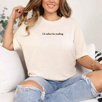 May include a person wearing a cream I'd Rather Be Reading T-Shirt featuring trendy book lover graphic and relaxed fit.
