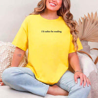 May include a person wearing a daisy I'd Rather Be Reading T-Shirt featuring trendy book lover graphic and relaxed fit.
