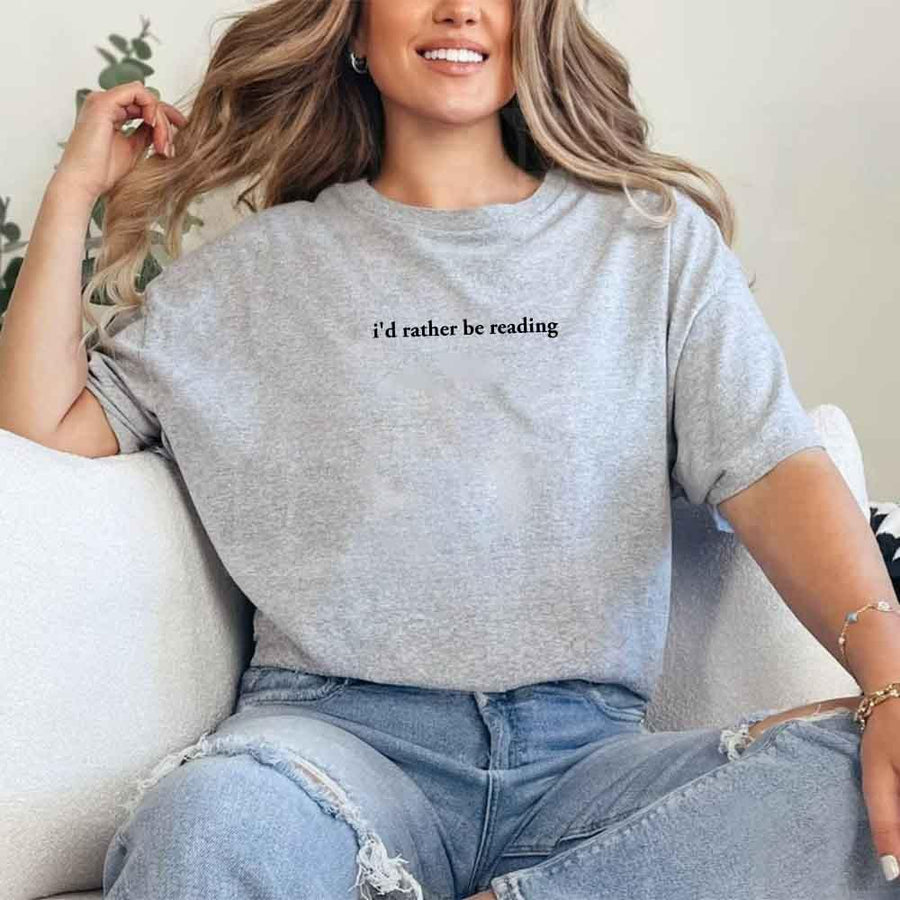 May include a person wearing a grey I'd Rather Be Reading T-Shirt featuring trendy book lover graphic and relaxed fit.
