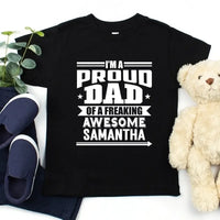 May include a father and child wearing matching t-shirts reading “I’m A Proud Dad” and “Me”