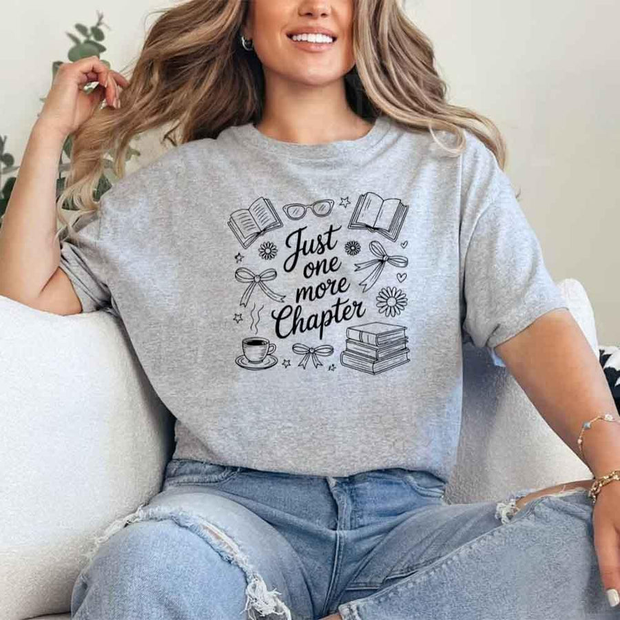 May include a person wearing a Sport Grey Just One More Chapter T-Shirt featuring trendy book lover graphic and relaxed fit.